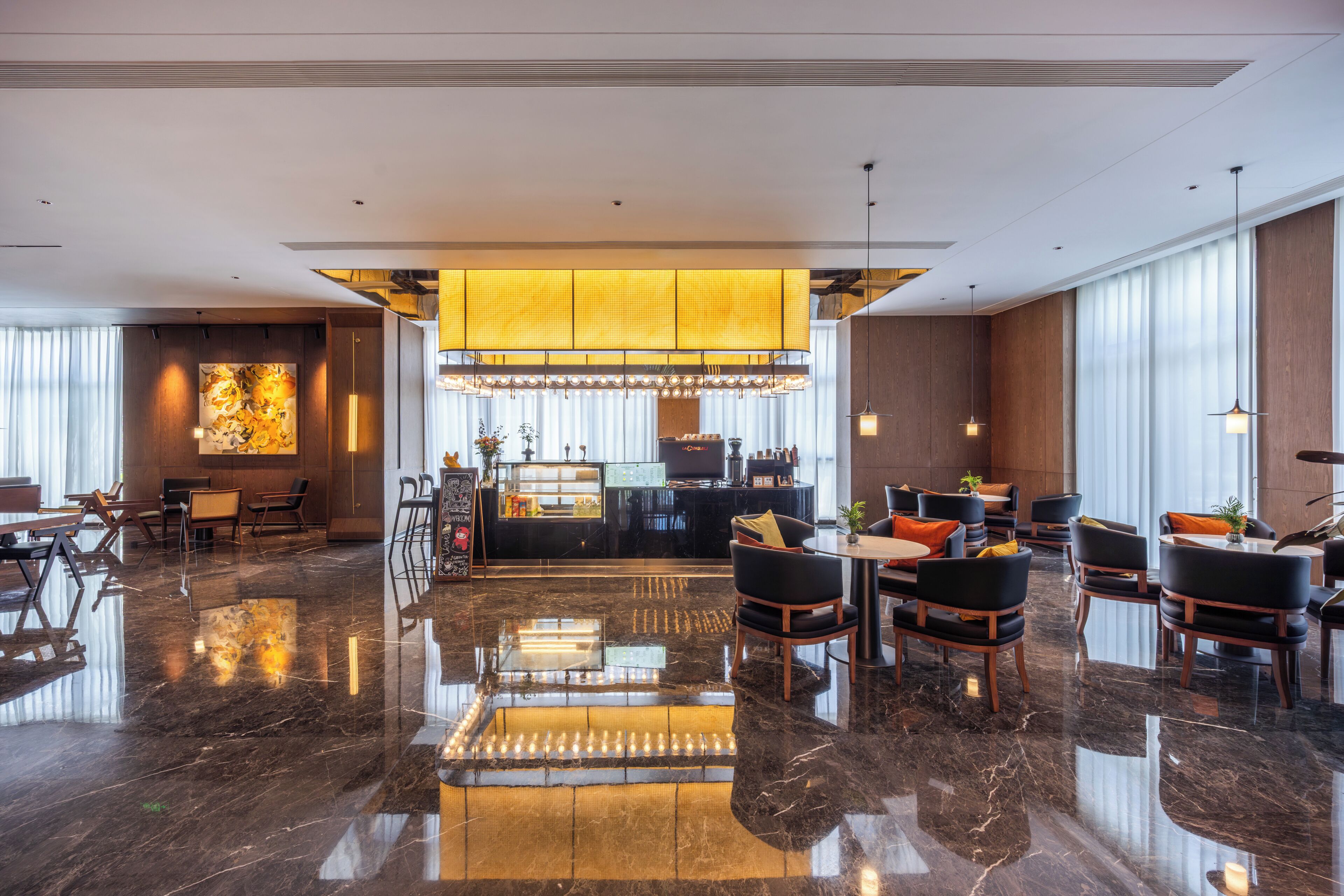 A modern hotel lobby with a polished marble floor, a central bar area, and seating arrangements.