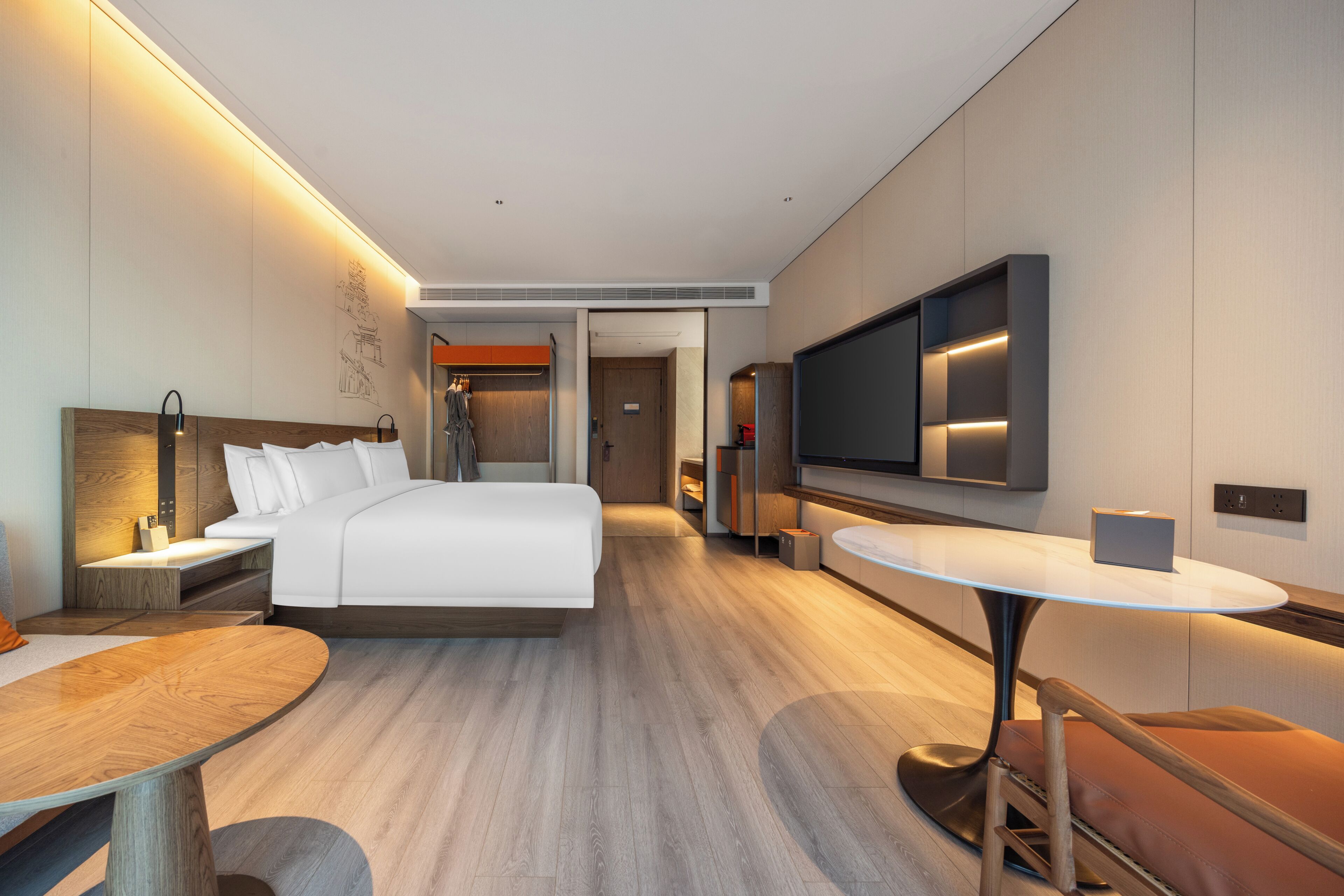 Une chambre d’hôtel moderne équipée d’un grand lit, d’une télévision, d’une table à manger et d’un coin salon.