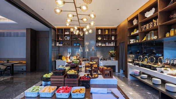 Un'area buffet con diversi cibi, un lampadario e scaffali con stoviglie.