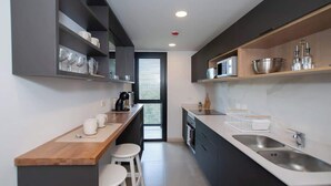 A modern kitchen with a wooden countertop, two bar stools, a built-in oven, and a large sink. - Corporate Stays Alban 1 (Asunción)