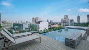 A rooftop infinity pool with lounge chairs, a stone accent wall, and a cityscape view. - Corporate Stays Alban 1 (Asunción)