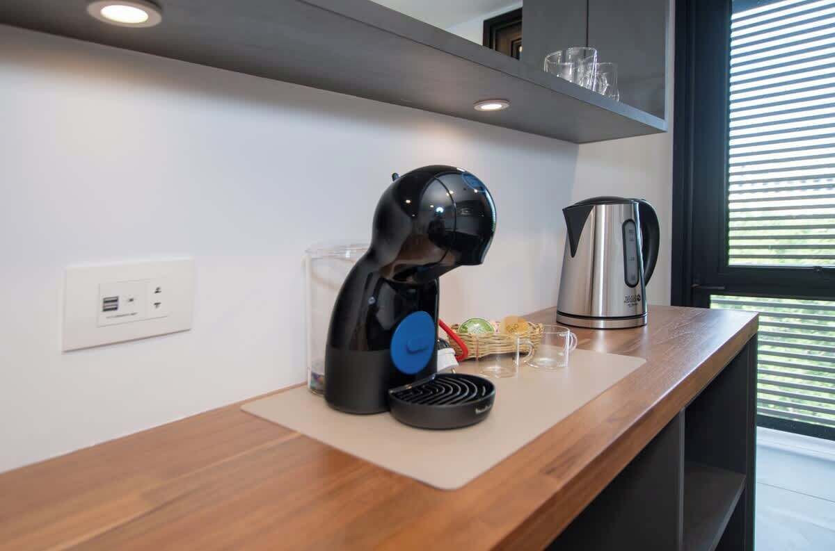 A modern kitchen with a kettle, a coffee maker, and a glass of water on the counter.