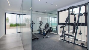 A modern gym with exercise equipment, large windows, and a glass partition. - Corporate Stays Alban 1 (Asunción)