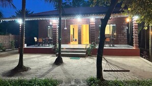 Un edificio de ladrillo con porche, mobiliario exterior y una entrada bien iluminada.