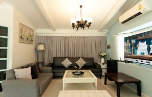 A living room with a sofa, a coffee table, a TV, and a painting on the wall. - MaMa Beach Pool Villa Pattaya (Muang Pattaya)