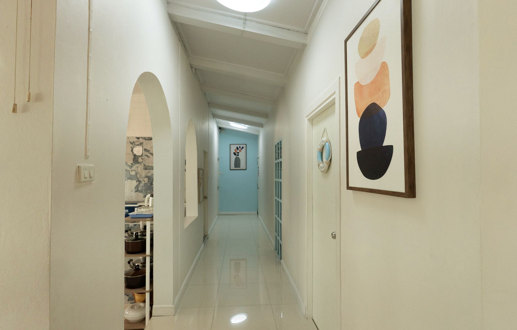 A hallway with a tiled floor, white walls, and a door at the end.