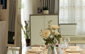 A dining table with a vase of flowers, wine glasses, and plates set for a meal. - MaMa Beach Pool Villa Pattaya (Muang Pattaya)