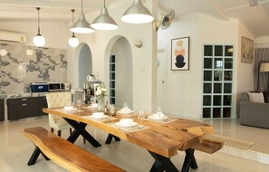 A modern dining area with a wooden table set for six, black metal legs, and pendant lights. - MaMa Beach Pool Villa Pattaya (Muang Pattaya)