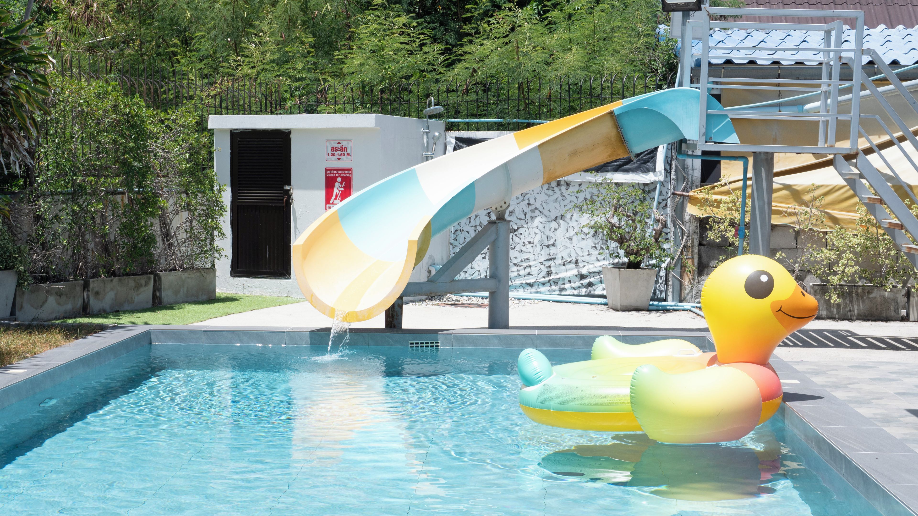 Una piscina con tobogán, un flotador de pato y una fuente de agua.