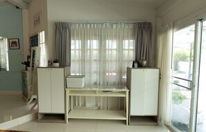 A room with a white desk, two cabinets, a window with sheer curtains, and a view of the outside. - MaMa Beach Pool Villa Pattaya (Muang Pattaya)