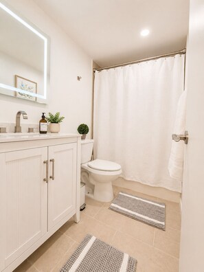 Ein Badezimmer mit Toilette, Waschbecken, Spiegel und Duschvorhang.