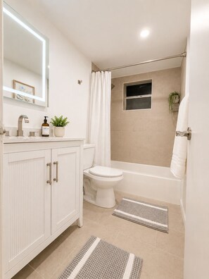 A modern bathroom with a toilet, sink, and bathtub.