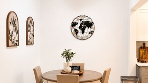 A dining area with a round table, six chairs, a world map wall decoration, two framed floral artworks, and a potted plant. - Apartment in Hollywood Beach, a 10-minute drive from the beach (Hollywood)