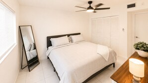 A bedroom with a bed, a ceiling fan, a bedside table with a lamp, a mirror, and a wardrobe. - Apartment in Hollywood Beach, a 10-minute drive from the beach (Hollywood)