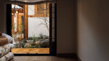 A traditional Japanese room with tatami flooring, a shoji screen door, and a view of a garden with rocks and plants.