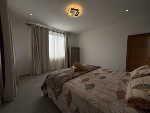 A bedroom with a bed, curtains, a radiator, and a door. - Cozy Luxe - 4 bedrooms Villa with private pool (Mahebourg)