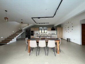 A modern kitchen with a dining area, a staircase, and a clock on the wall. - Cozy Luxe - 4 bedrooms Villa with private pool (Mahebourg)