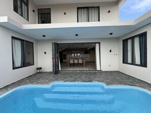 A modern two-story house with a swimming pool, large windows, and a dining area visible through an open door. - Cozy Luxe - 4 bedrooms Villa with private pool (Mahebourg)