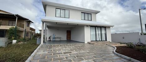 A modern two-story house with a covered patio and a paved driveway.