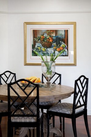 Une table à manger avec des chaises, un vase rempli de fleurs et un tableau accroché au mur.