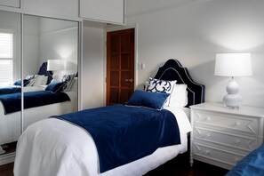 A bedroom with a bed, a dresser, a mirror, and a door.