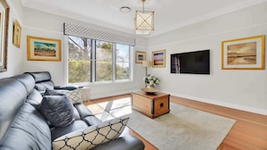 A modern living room with a leather sofa, a wooden sideboard, and artwork on the walls.