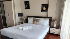 A hotel room with a bed, bedside tables, a wardrobe, and framed pictures on the wall. - Deluxe Studio Apartment at Eldon Hotel Apartments (Nairobi)