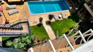 A rectangular swimming pool with a stone deck, surrounded by lounge chairs and potted plants. - Deluxe Studio Apartment at Eldon Hotel Apartments (Nairobi)