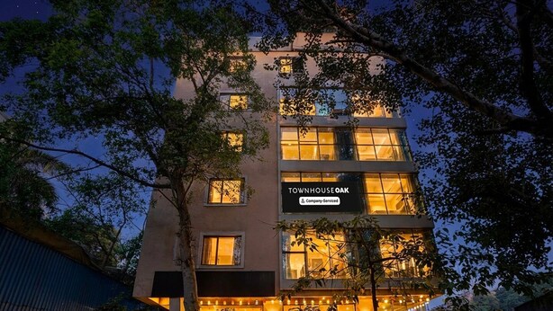 Un edificio de varios pisos con un cartel que dice 'TOWNHOUSE OAK' y 'Servicio de Empresa'.