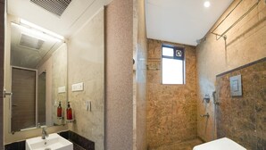 Un baño con lavamanos blanco, un espejo, ducha e inodoro.