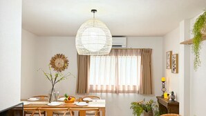 Ein modernes Wohnzimmer mit Essbereich, Holzmöbeln, einem Fernseher und einer Pendelleuchte.