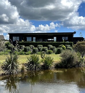 A modern building with a water feature in front. - Hidden Treasure in Mangawhai Village + EV charger (Mangawhai)