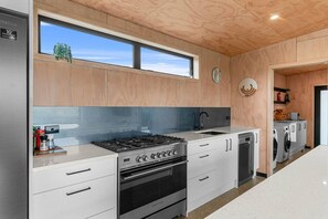 Eine moderne Küche mit einem Edelstahlherd, weißen Schränken, einem Einbauofen und einem Fenster über der Spüle.