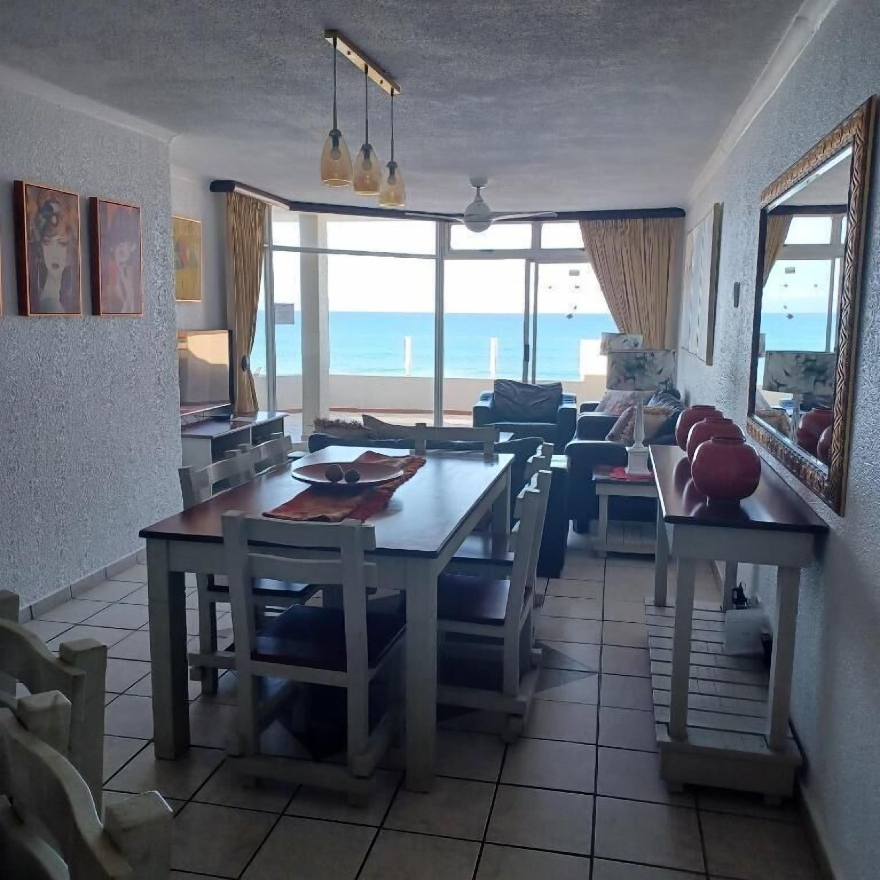 Ein Essbereich mit Meerblick, einem Deckenventilator und einem großen Spiegel.