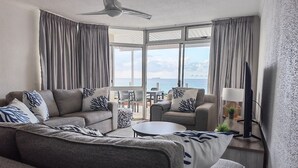 A modern hotel room with a sofa, armchair, and a small table.