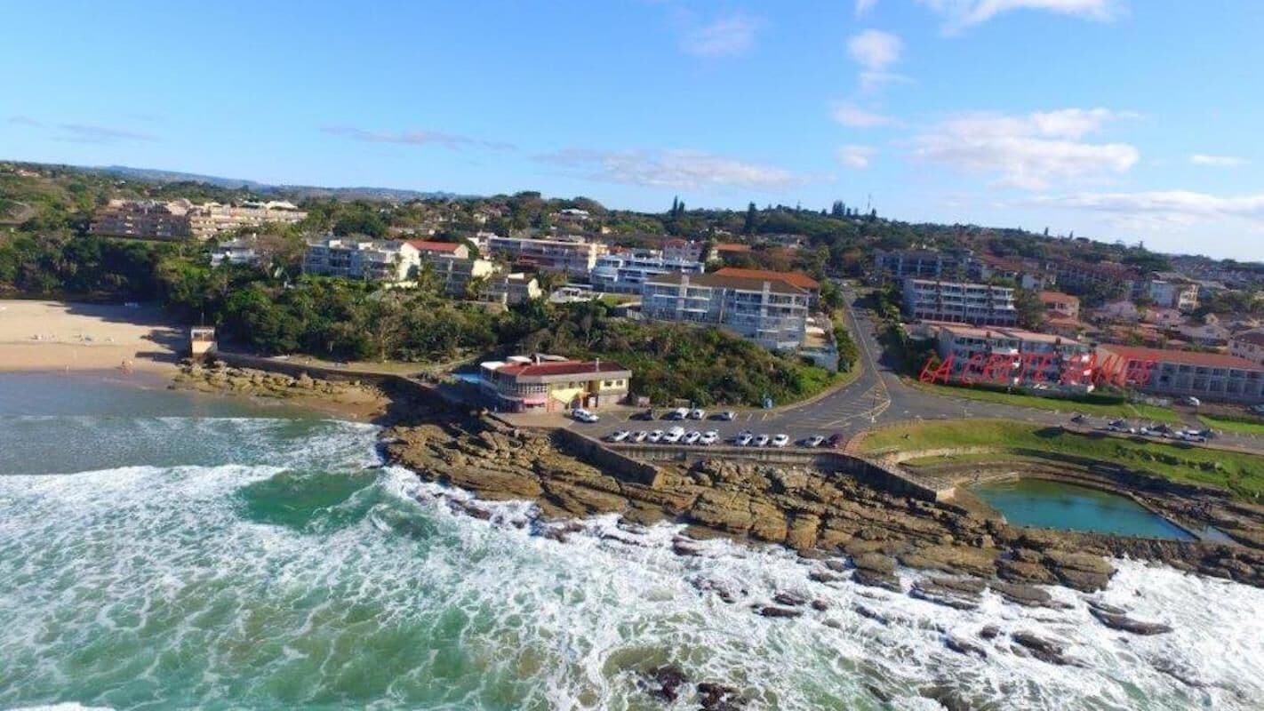 A coastal town with buildings, a beach, and rocky coastline.