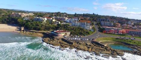 A coastal town with buildings, a beach, and rocky coastline.