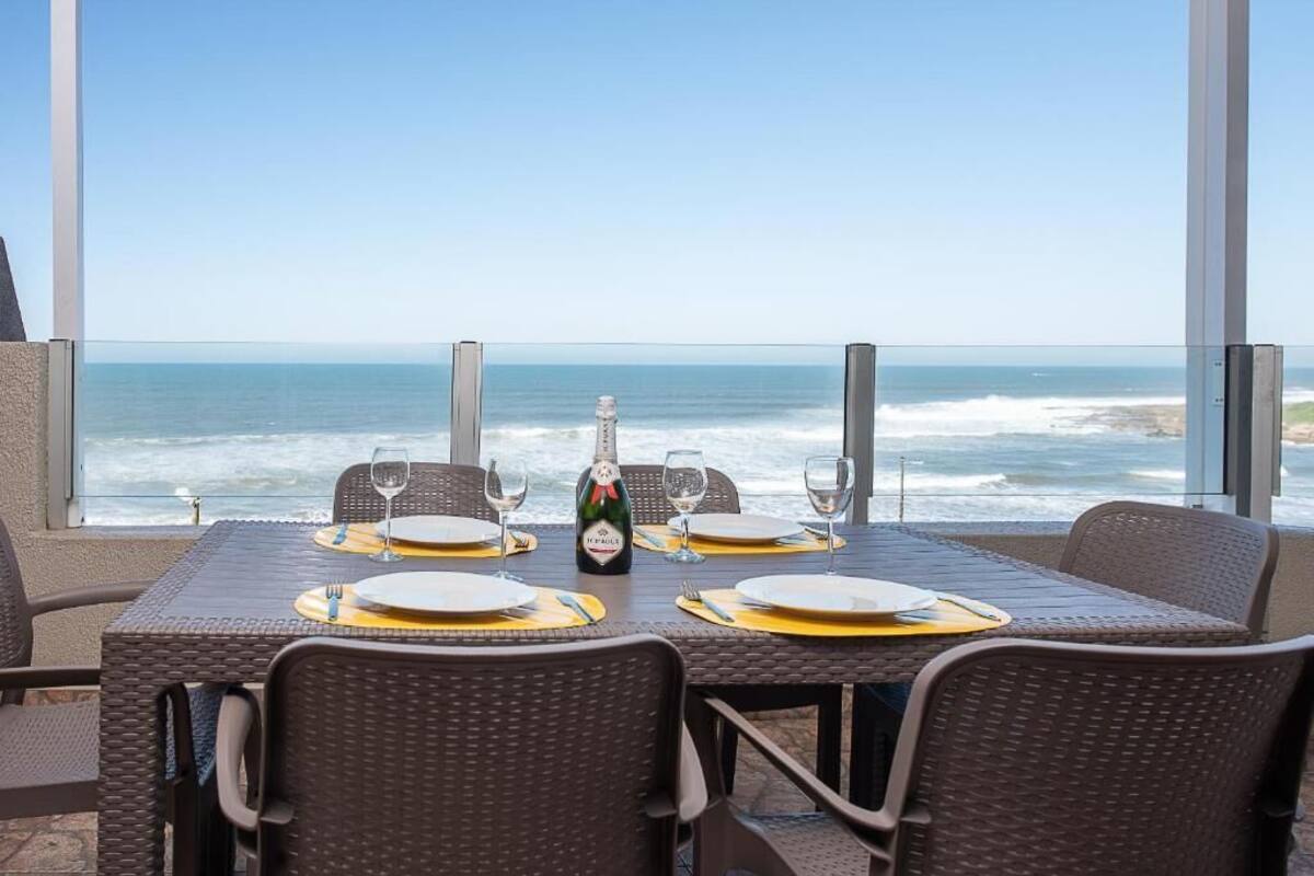 Een tafel voor vier gedekt, met een fles champagne, met uitzicht op zee.