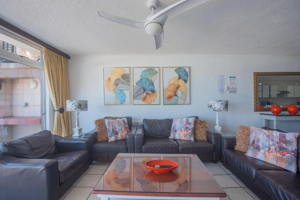 A living room with a ceiling fan, a sofa set, a coffee table, and abstract wall art.
