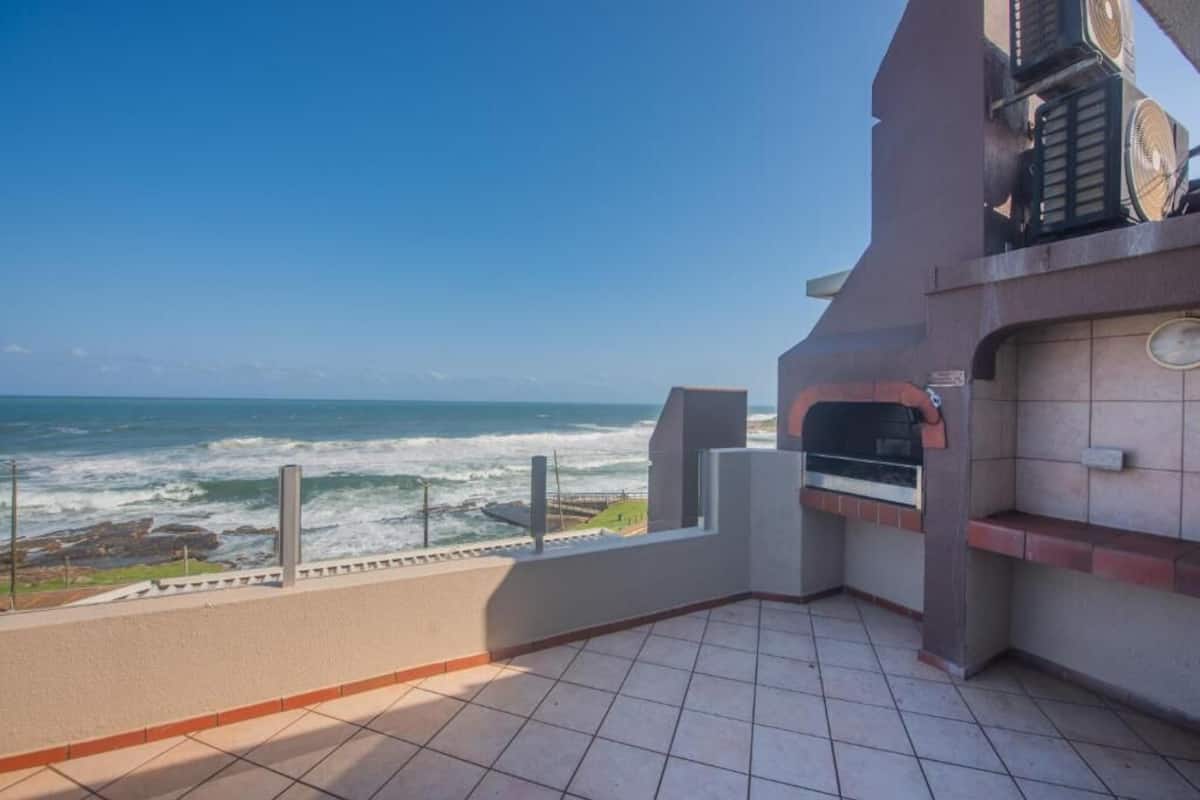 Un balcon avec vue sur l’océan, un four en briques et un sol carrelé.