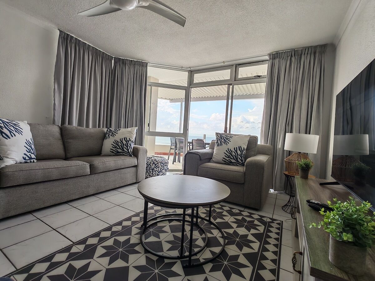 A modern living room with a sofa, a round coffee table, and a TV.