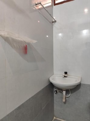 A bathroom with a white sink, a shower with a glass door, and a towel rack.