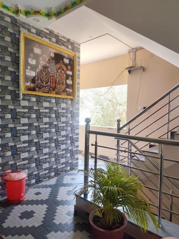 A staircase with metal railings, a tiled floor, a potted plant, and a framed picture on the wall.