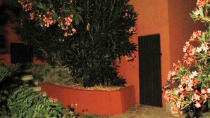 Un edifici amb teulada de rajola i un jardí amb plantes florents.