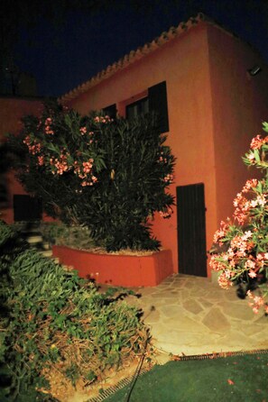 A building with a tiled roof and a garden with flowering plants. - Villa Oasis Provençale 3 étoiles avec piscine, jacuzzi, terrain de pétanque. (Cavalaire-sur-Mer)