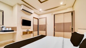 Una camera d'albergo con un letto, una TV, un minibar e un armadio.