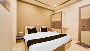 Una camera d'albergo con un letto grande, un comodino, uno specchio, un armadio e una porta.