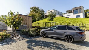 A modern building with a sloped roof, a gravel driveway, and a parked car. - Wellness retreat with a hot tub and fitness center overlooking the lake (Vaivre-et-Montoille)
