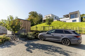 Ein modernes Gebäude mit geneigtem Dach, einer Schotterauffahrt und einem geparkten Auto.