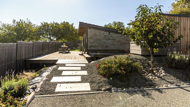 A modern outdoor patio with a wooden deck, stone pathway, and a small tree. - Wellness retreat with a hot tub and fitness center overlooking the lake (Vaivre-et-Montoille)